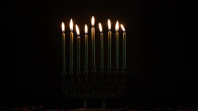 Burning candles on menorah in dark room for Hanukkah.