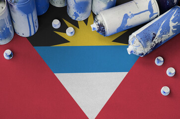 Antigua and Barbuda flag and few used aerosol spray cans for graffiti painting. Street art culture...