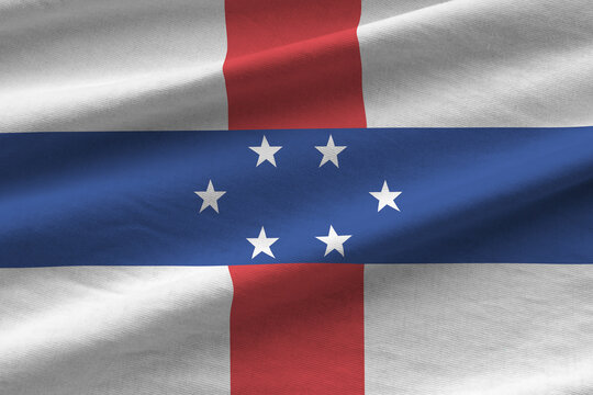Netherlands Antilles flag with big folds waving close up under the studio light indoors. The official symbols and colors in banner
