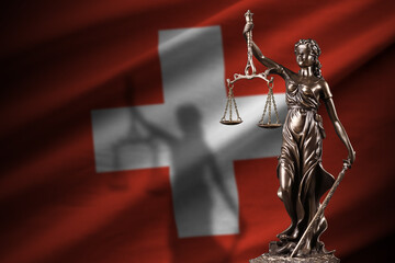 Switzerland flag with statue of lady justice and judicial scales in dark room. Concept of judgement...