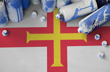 Guernsey flag and few used aerosol spray cans for graffiti painting. Street art culture concept
