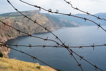 military border of barbed wire at sea in the mountains