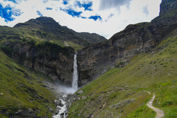 Beautiful tall glacier melt waterfall with beautiful grass area. Sissu, lahaul, Himachal pradesh, India