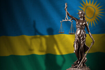 Rwanda flag with statue of lady justice and judicial scales in dark room. Concept of judgement and...