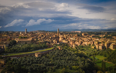 Fototapeta na wymiar Scenery of Siena, a beautiful medieval town in Tuscany, view of the Dome and Bell Tower of Siena Cathedral, landmark Mangia Tower and Basilica of San Domenico,Italy. Aerial drone shot, october 2022