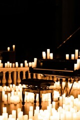Chair and piano in a dark room surrounded by candles