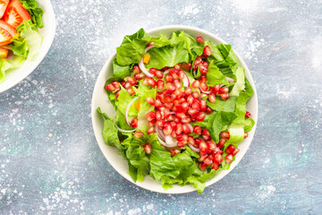 Healthy food pomegranate vegetable salad in bowl on blue wood background.