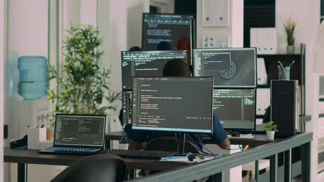 Multiethnic group of programers working on server code to develop new database user interface on computers. IT engineers coding html script with artificial intelligence on terminal window.