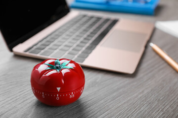 Kitchen timer in shape of tomato and laptop on wooden table, space for text - obrazy, fototapety, plakaty