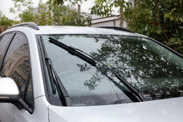 Obraz premium Wipers cleaning raindrops from car windshield outdoors