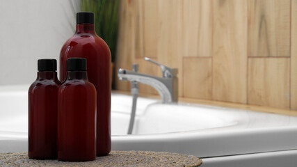 Naklejka premium Bath foam and other personal hygiene products in bottles on wicker mat in bathroom, space for text