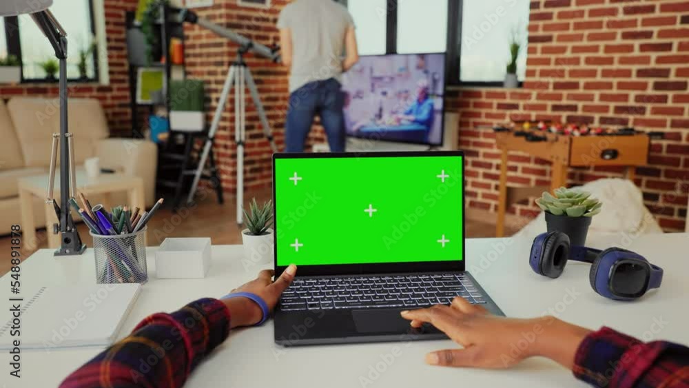 Poster young adult working on laptop with isolated green screen on display, showing chroma key background a