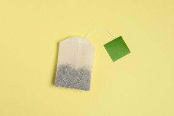 New tea bag with tab on beige background, top view