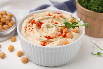 Delicious hummus with chickpeas and paprika served on white table, closeup