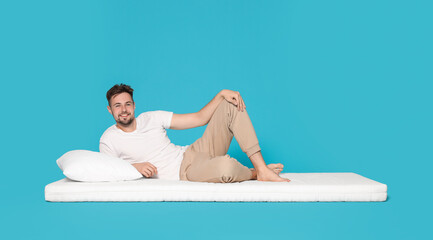 Man lying on soft mattress against light blue background