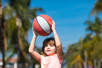 Little child boy playing basketball with basket ball. Kid with basket ball on sky background, cheerful and pleasant.