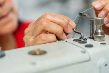 Fototapeta na wymiar Woman fixing the threads of a sewing machine in a workshop