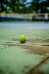 court tennis ball on cement floor with net in background in competition sport arena
