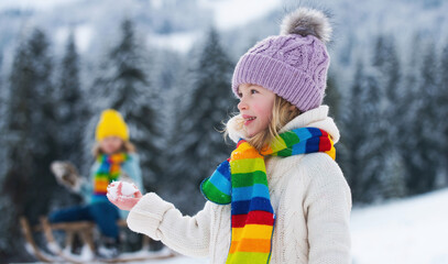Little girl and boy enjoying a day out playing in the winter forest. Children having fun in winter park.