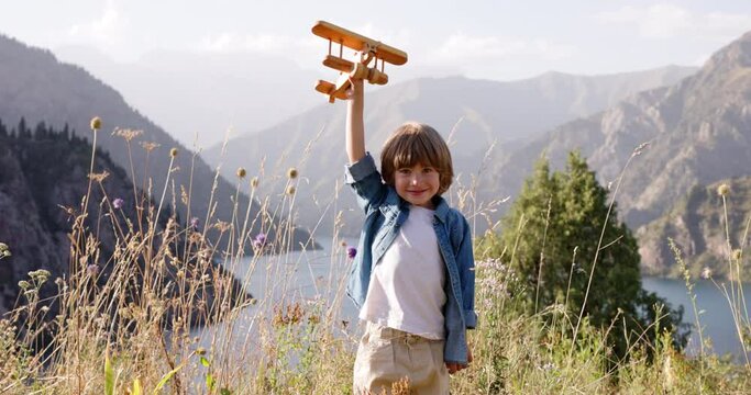 Happy dreamer little boy 4-5 years with toy wood airplane close up, childhood dream to become airplane pilot, portrait of happy caucasian boy smiles at camera, Children's dreams concept. child smiling