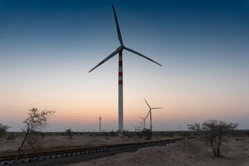 Pre dawn light in desert sky with Electrical power generating wind mills producing alterative eco friendly green energy for consumption by local people. Thar desert, Rajasthan, India.