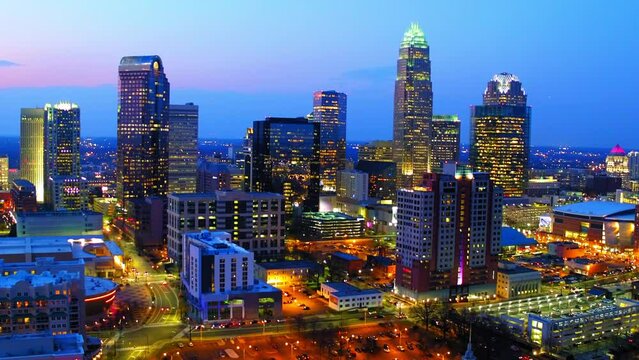 Aerial Shot Of Illuminated Modern City Against Cloudy Sky, Drone Flying Backwards Over Buildings During Dusk - Charlotte, North Carolina