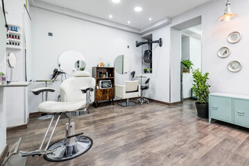 Beauty salon with white leatherette sofas and circular mirrors on the walls