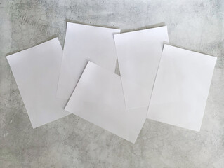 Five 5 sheets of A4 paper scattered on a concrete background