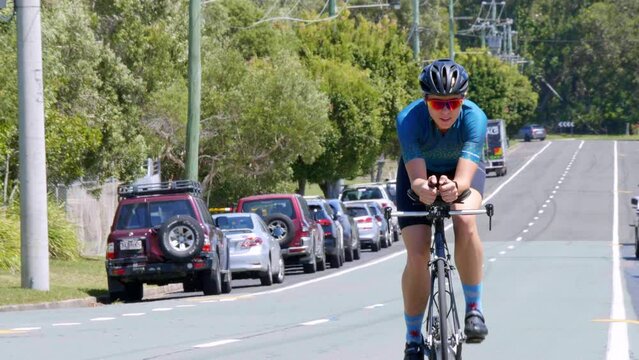 Fit Female Cyclist In Lycra Riding Bike Through Suburban Street, 4K Slow Motion