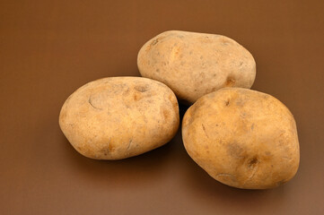 Three potatoes on a brown background