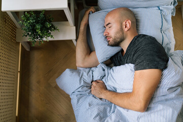 Top view of a young man sleeping in bed