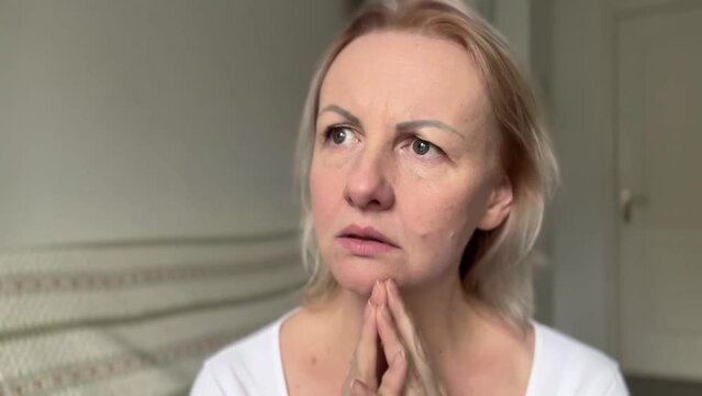 Adult beautiful woman with blond hair surprised She sticks out lip and looks perplexedly to right and left. She opens her eyes wide and looks into the frame brings her hands to her lips on both sides