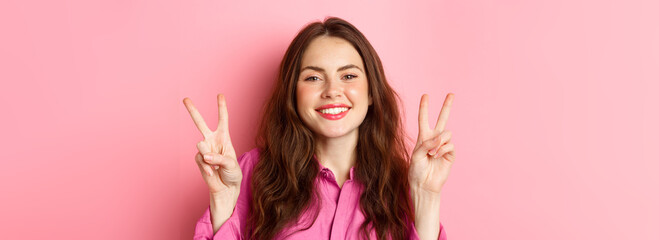 Close up of positive brunette female model showing peace signs, smiling and having fun, good vibes...