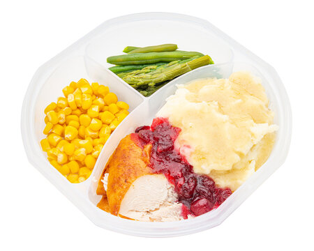 Holiday dinner in a lunch box. Mashed potatoes, turkey, gravy, cranberry sauce, corn, green beans, asparagus. Happy Thanksgiving day. Macro high resolution photo. White isolated background. Food Photo