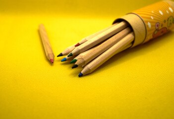Photo of box with pencils on yellow background