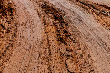 Tire tracks from the wheels of passing cars in the wet, softened ground on a muddy rural road. Mult...