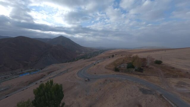White car ready to driving on serpentine asphalt road dry desert mountain countryside aerial view. FPV sport drone shot automobile journey rocky terrain travel picturesque cliff valley dramatic sky 4k