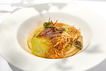 Roasted fish with crispy skin, celery cream and fresh herbs espuma. Fried halibut fillet on mashed...