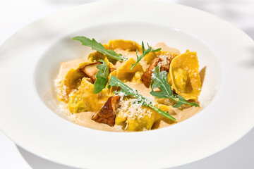 Italian ravioli with meat and mushroom sauce on white plate. Meat tortellini with creamy sauce in summer menu with shadows of tree leaves Ravioli stuffed beef in elegant style