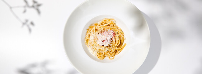 Spaghetti with crab meat and cheese on white table with shadows. Seafood pasta with spaghetti and...