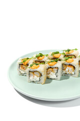 Maki sushi with sesame outside, tempura shrimp inside topped spicy sauce and microgreens. Spicy shrimp maki roll on ceramic plate isolated on white background Sushi roll with crispy prawn on plate