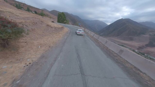 Automobile speed drift racing extreme driving on mountain serpentine asphalt road turning around aerial view. FPV sports drone shot white car drifting burning smoke diffusion race spin track cliff 4k