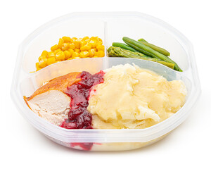 Holiday dinner in a lunch box. Mashed potatoes, turkey, gravy, cranberry sauce, corn, green beans, asparagus. Happy Thanksgiving day. Macro high resolution photo. White isolated background. Food Photo