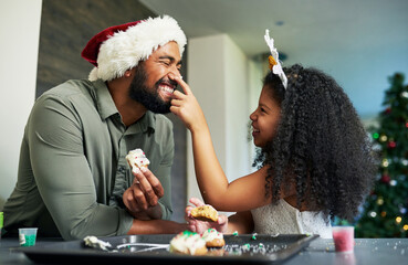 Christmas, father and kid with cookie, food fight and playful, celebrate and holiday fun at home. Happy family, man with girl and love, baker dessert and celebration, happiness and xmas at home.