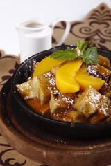 Bread pudding with peach slices and caramelized sugar served on a skillet