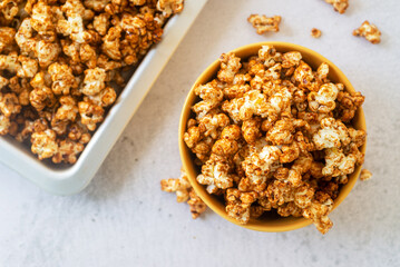 homemade salted caramel butter popcorn in yellow ceramic bowl on marble background.