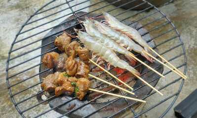Fresh prawns skewered and marinated pig large intestines grilled over charcoal for seafood and...