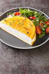 Airy french Poulard omelette served with fresh salad close-up on a plate on the table. Vertical