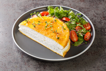 Delicate french Poulard omelette with beaten egg whites served with fresh salad close-up on a plate on the table. horizontal