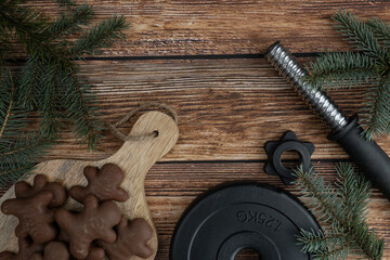 Chocolate gingerbread Christmas cookies, tree branches and heavy dumbbell barbell weight plate....